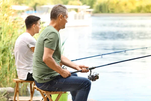 Jovem e seu pai pescando no rio — Fotografia de Stock