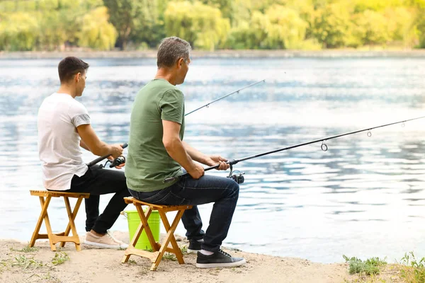 Genç adam ve babası nehirde balık tutuyor. — Stok fotoğraf