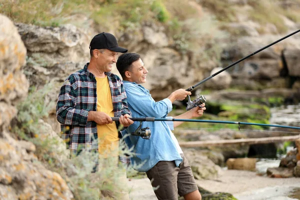Молодий чоловік і його батько рибалять на річці — стокове фото