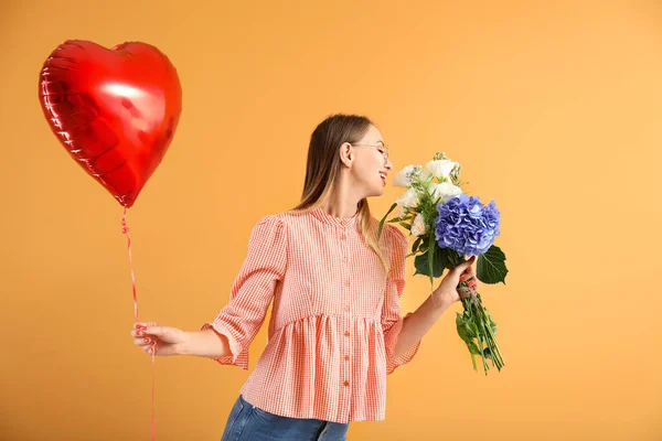 Beautiful young woman with air balloon and flowers on color background — Stock Photo, Image