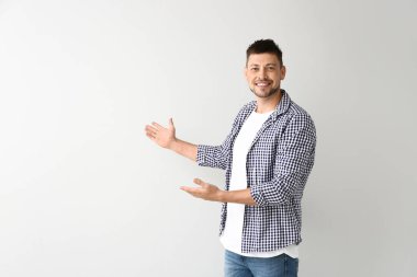 Yakışıklı adam arka planda bir şeyler gösteriyor.