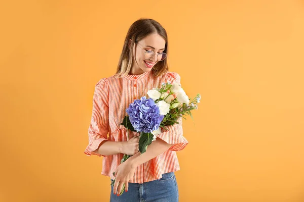 Bella giovane donna con fiori su sfondo a colori — Foto Stock