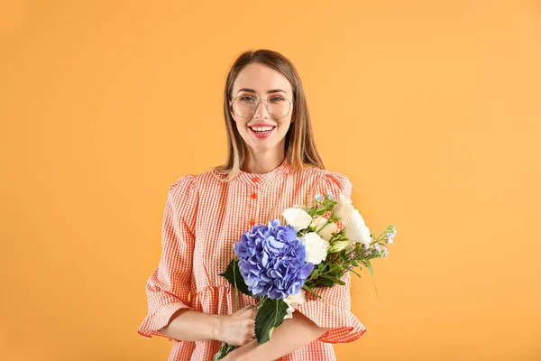 Beautiful young woman with flowers on color background — Stock Photo, Image