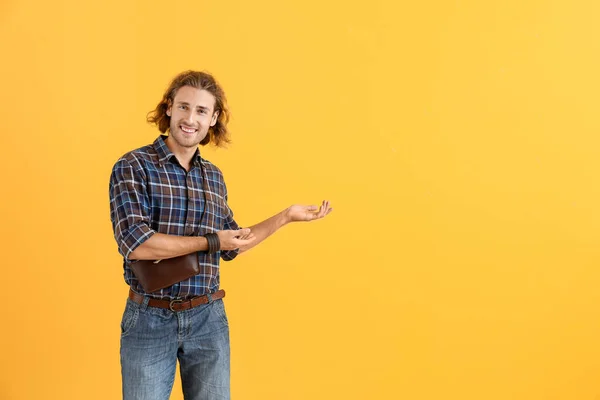 Handsome man pointing at something on color background — Stock Photo, Image
