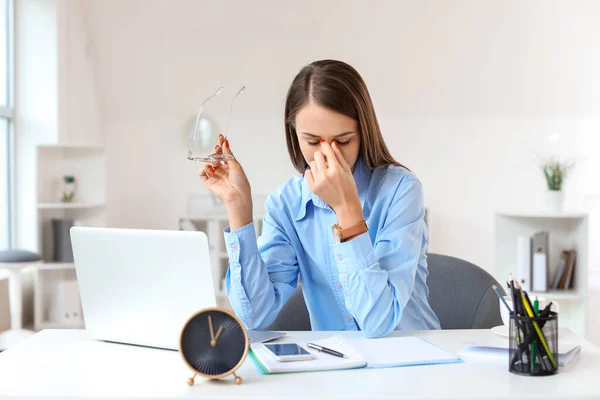 Tired young woman trying to meet deadline in office — Stock Photo, Image