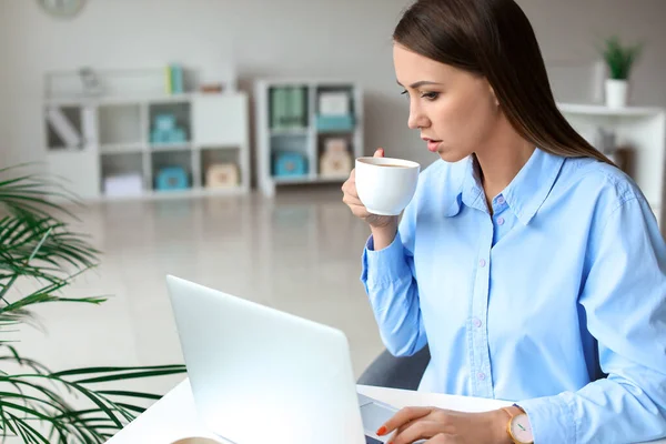 Jeune femme buvant du café tout en travaillant au bureau — Photo