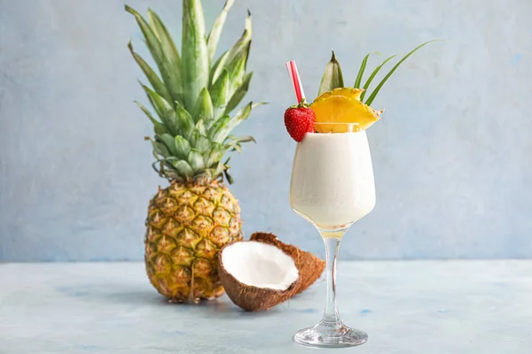 Glass of tasty Pina Colada cocktail and fruits on table — стокове фото