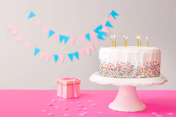 Tasty Birthday cake with gift on table against grey background — Stock Photo, Image