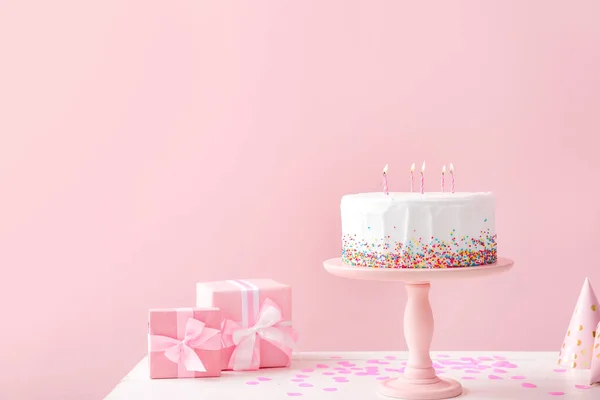 Tasty Birthday cake with gifts on table against color background — Stock Photo, Image
