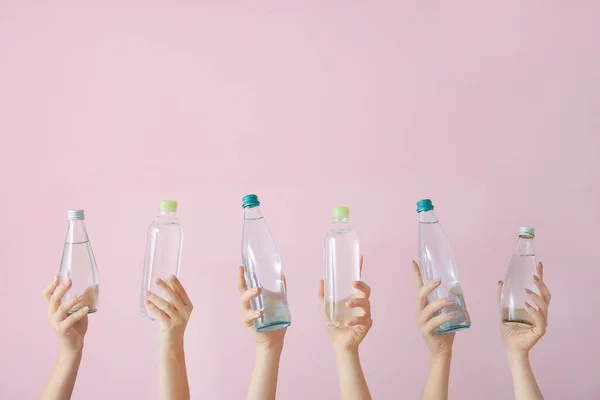 Γυναικεία χέρια με μπουκάλια νερό στο φόντο χρώμα — Φωτογραφία Αρχείου