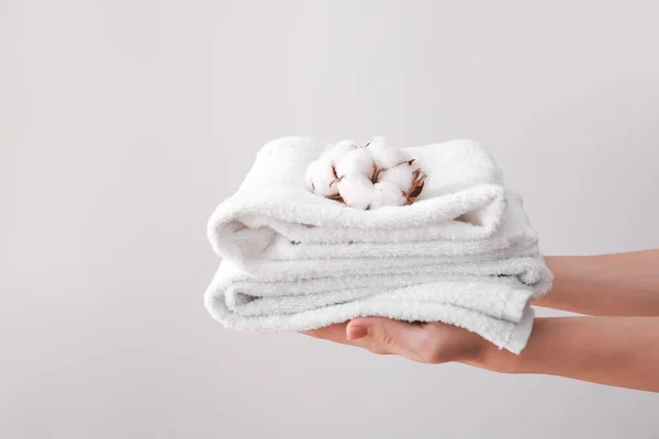 Mãos femininas com belas flores de algodão e toalhas macias em fundo cinza — Fotografia de Stock