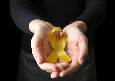 Siyah arka planda sarı kurdeleli kadın, yakın plan. Kanser farkındalığı kavramı