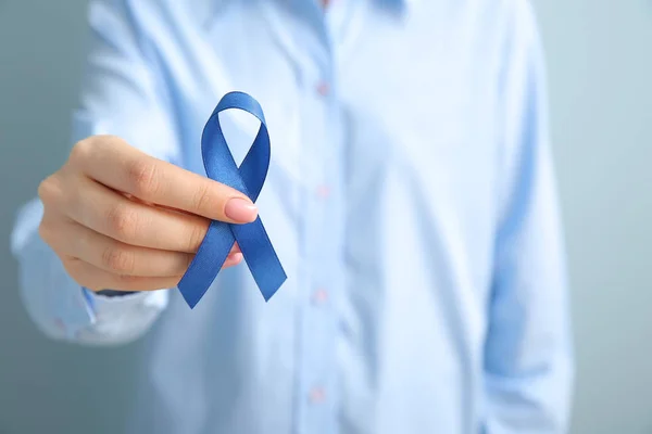 Mujer joven con cinta azul sobre fondo gris, primer plano. Concepto de concienciación — Foto de Stock