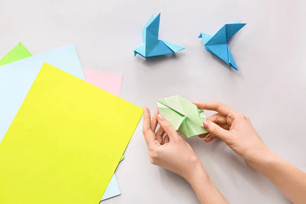 Mujer haciendo figuras de origami en la mesa — Foto de Stock