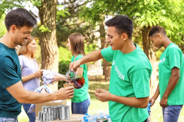 Молоді добровольці дають їжу бідним людям на відкритому повітрі — стокове фото