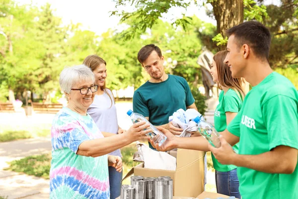 Młodzi wolontariusze dający darowiznę biednym ludziom na świeżym powietrzu — Zdjęcie stockowe