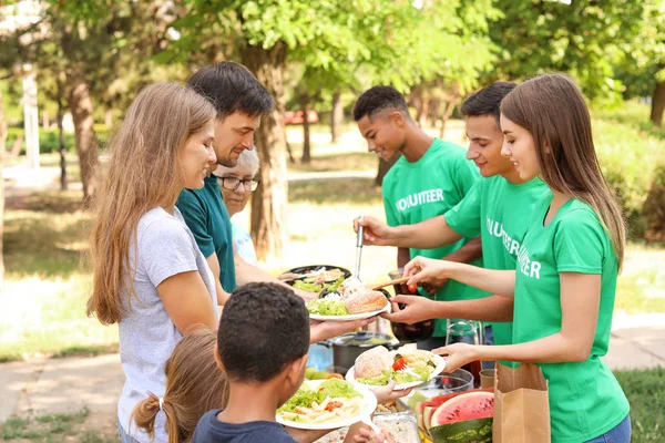 Jóvenes voluntarios dando comida a los pobres al aire libre — Foto de Stock