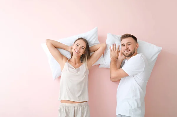 Молодая пара с подушками на цветном фоне — стоковое фото