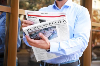 Dışarıda gazetesi olan yakışıklı bir adam.