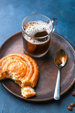 Lezzetli çörekli tabak ve arka planda bir fincan kahve.