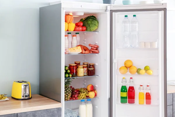 Open big fridge with products in kitchen — Stock Photo, Image