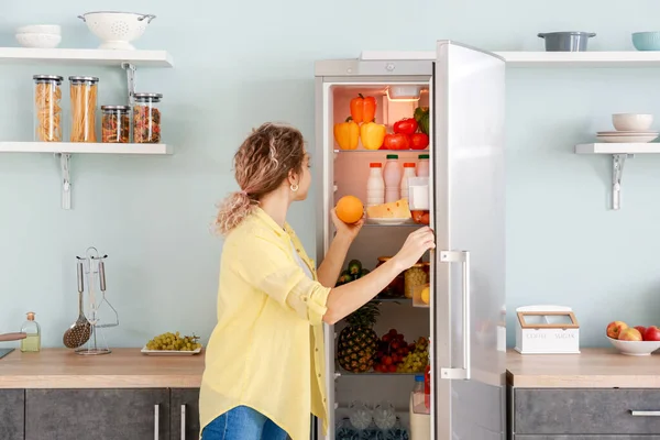 Жінка вибирає їжу в сучасному холодильнику вдома — стокове фото