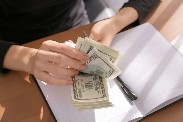 Vrouw die dollarbankbiljetten aan tafel telt — Stockfoto