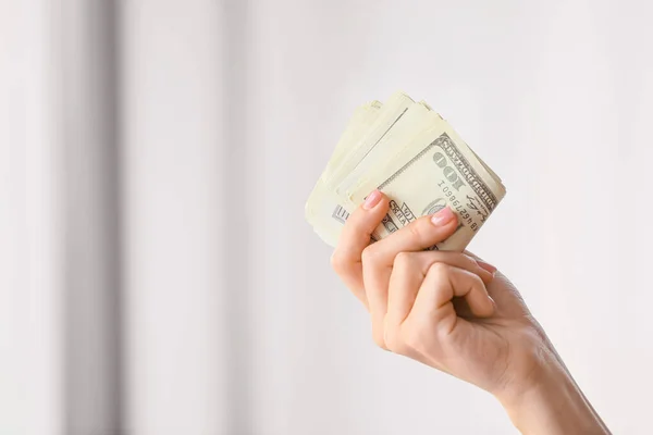 Mão feminina com notas de dólar sobre fundo claro — Fotografia de Stock