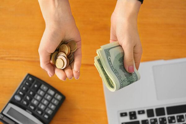 Руки женщины с долларовыми банкнотами и монетами, вид сверху
