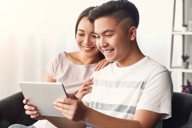 Evde tablet bilgisayarı olan mutlu bir Asyalı çiftin portresi.