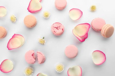 Beyaz arka planda çiçek yaprakları olan farklı lezzetli badem kurabiyeleri.