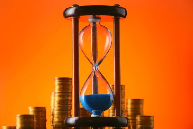 Renk arkaplanında bozuk paralar olan kum saati