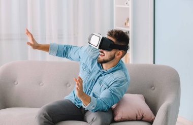 Evde sanal gerçeklik gözlüklü genç bir adam