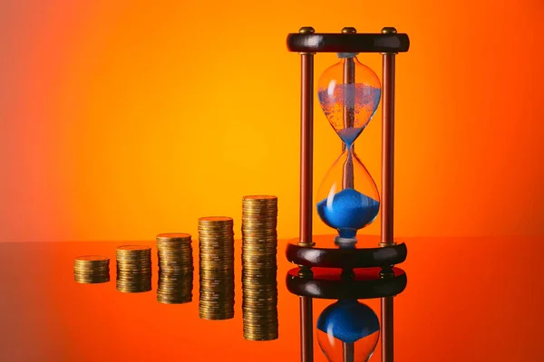 Hourglass with coins on color background — Stock Photo, Image