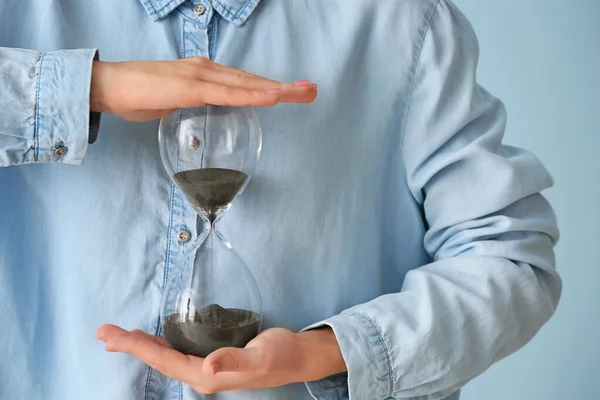 Woman with hourglass on color background, closeup — Stock Photo, Image