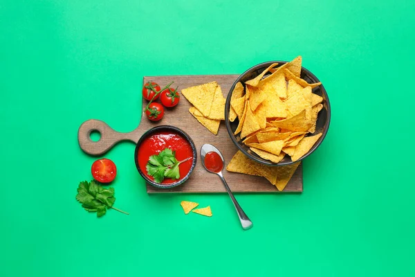 Cuenco con sabrosos nachos y salsa de tomate sobre fondo de color — Foto de Stock