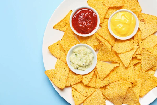 Placa con sabrosos nachos y salsas sobre fondo de color — Foto de Stock