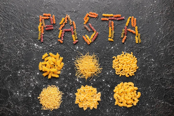 Composition with different uncooked pasta on dark background — Stock Photo, Image