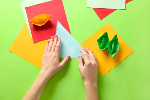 Woman making origami boats on color background — Stock Photo, Image
