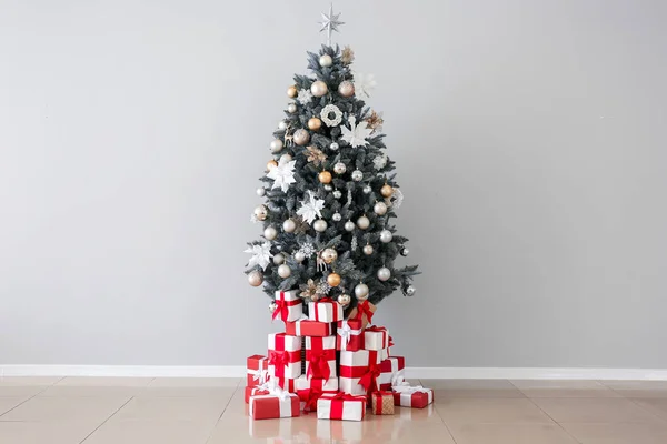 Árvore de Natal decorada e presentes perto da parede de luz — Fotografia de Stock