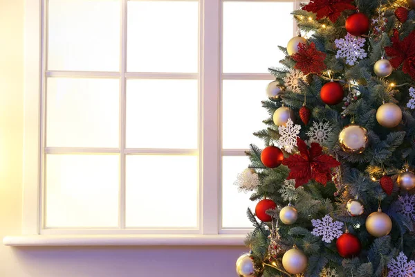 Gedecoreerde kerstboom in de buurt van raam in de kamer — Stockfoto