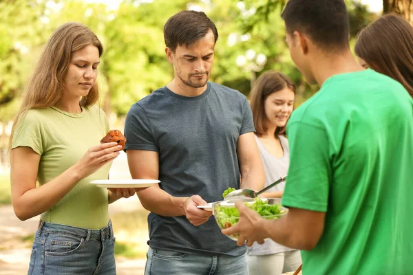 Junge Freiwillige verteilen Lebensmittel an arme Menschen im Freien — Stockfoto
