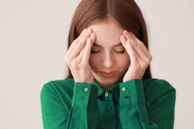 Genç kadın ışık arka plan üzerinde baş ağrısı muzdarip