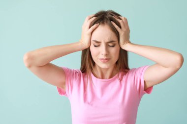 Young woman suffering from headache on color background clipart