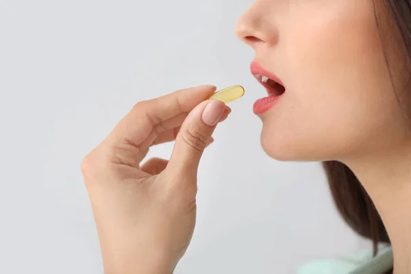 Young woman taking pill on light background, closeup — Stock Photo, Image