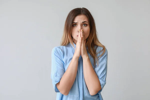 Portrait of worried young woman on light background — Stock Photo, Image