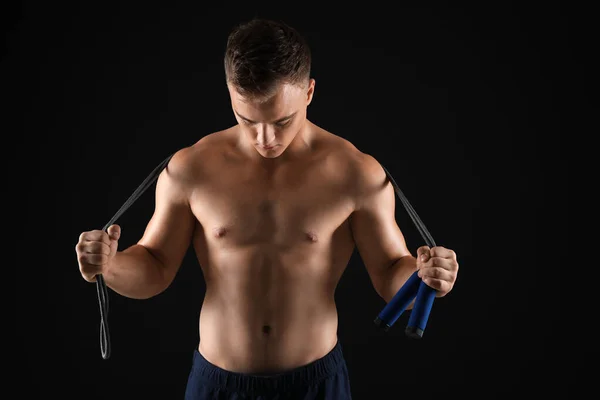 Schöner männlicher Bodybuilder mit Springseil auf dunklem Hintergrund — Stockfoto