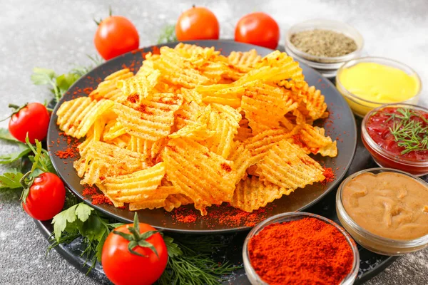 Plate with tasty potato chips, tomatoes and spices on table — Stock Photo, Image
