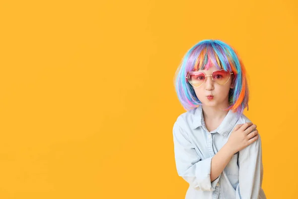 Niedliches kleines Mädchen in heller Perücke auf farbigem Hintergrund — Stockfoto
