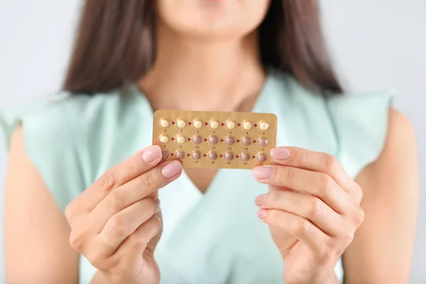 Mujer joven con pastillas sobre fondo claro, primer plano —  Fotos de Stock